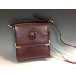 Cartier, a burgundy leather handbag, the fold-over top with embossed logo and adjustable shoulder