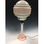 An Art Deco pink plastic table lamp, with original enamelled and gilded glass globe to a reeded