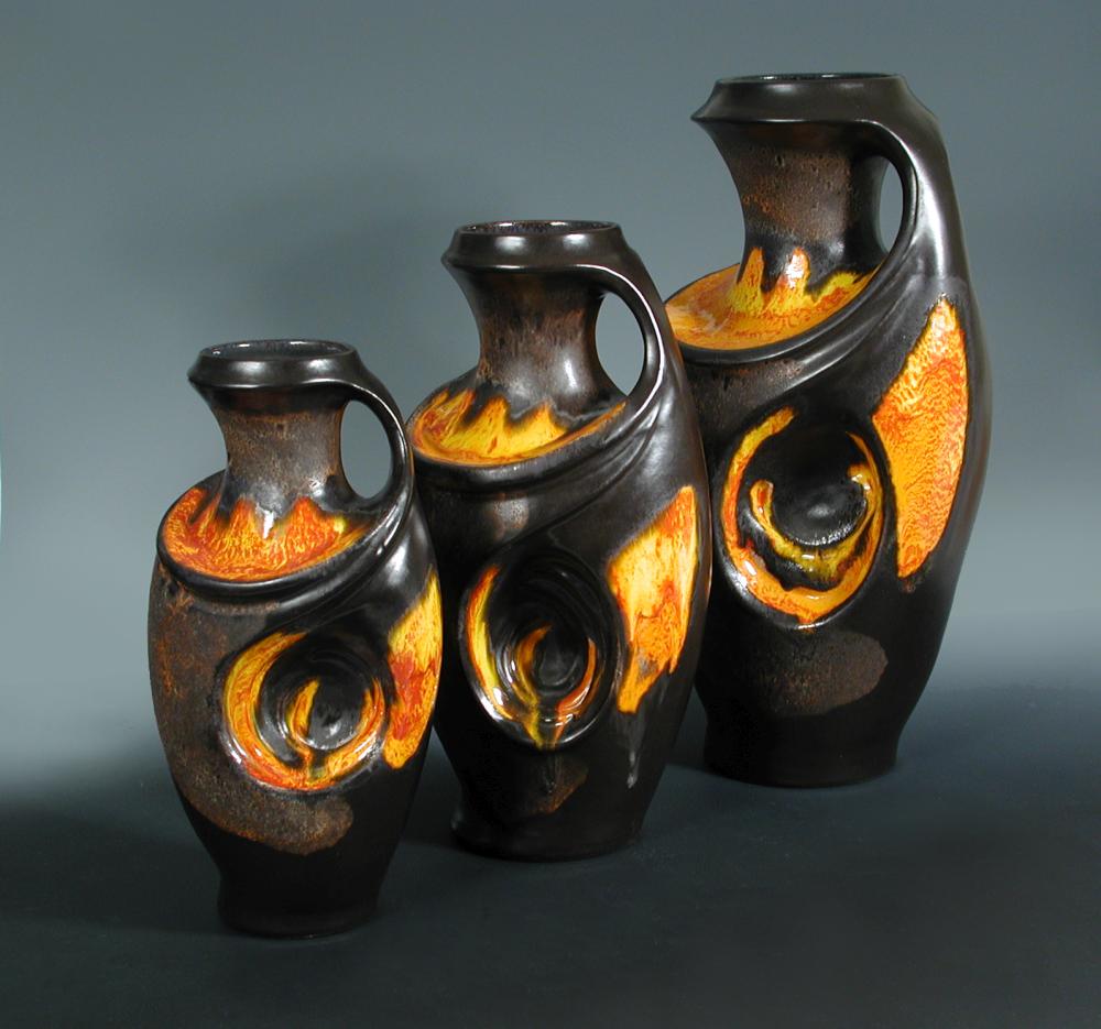 A graduated set of three German floor standing lava glazed vases, c.1960, each with integral handle,