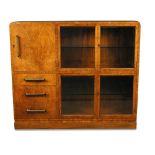 An Art Deco walnut cabinet, with two pairs of glazed panel doors to the right side, a cupboard and