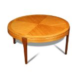 A mid-century blonde-wood coffee table, the quarter veneered circular top on four tapering legs 41 x