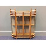 An Aesthetic period ash and oak glazed hanging cabinet, with curved ends and turned spindle uprights