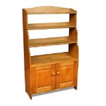 Attributed to Peter Waals, an oak waterfall bookcase, the open shelves above a two door cupboard