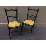 A pair of Aesthetic ebonised side chairs, the top rails painted with birds and foliage over caned