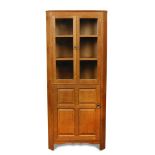 Attributed to Heal's, a glazed oak corner cupboard, with pair of glazed doors above a single