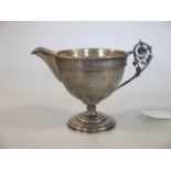 A late 19th century possibly Russian silver cream jug with stylised leaf cast handle and repeating