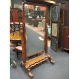 A William IV mahogany full length cheval mirror, with tapering octagonal columns, on scroll carved