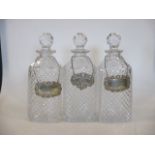 A set of three cut glass spirit decanters with silver labels