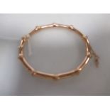 A 15ct faux bamboo style hinged bangle, with safety chain, 10g