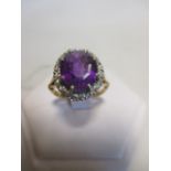 An 18ct amethyst and diamond ring, the oval amethyst, 11.2 x 9.6 x 6.2mm, claw set to a border of