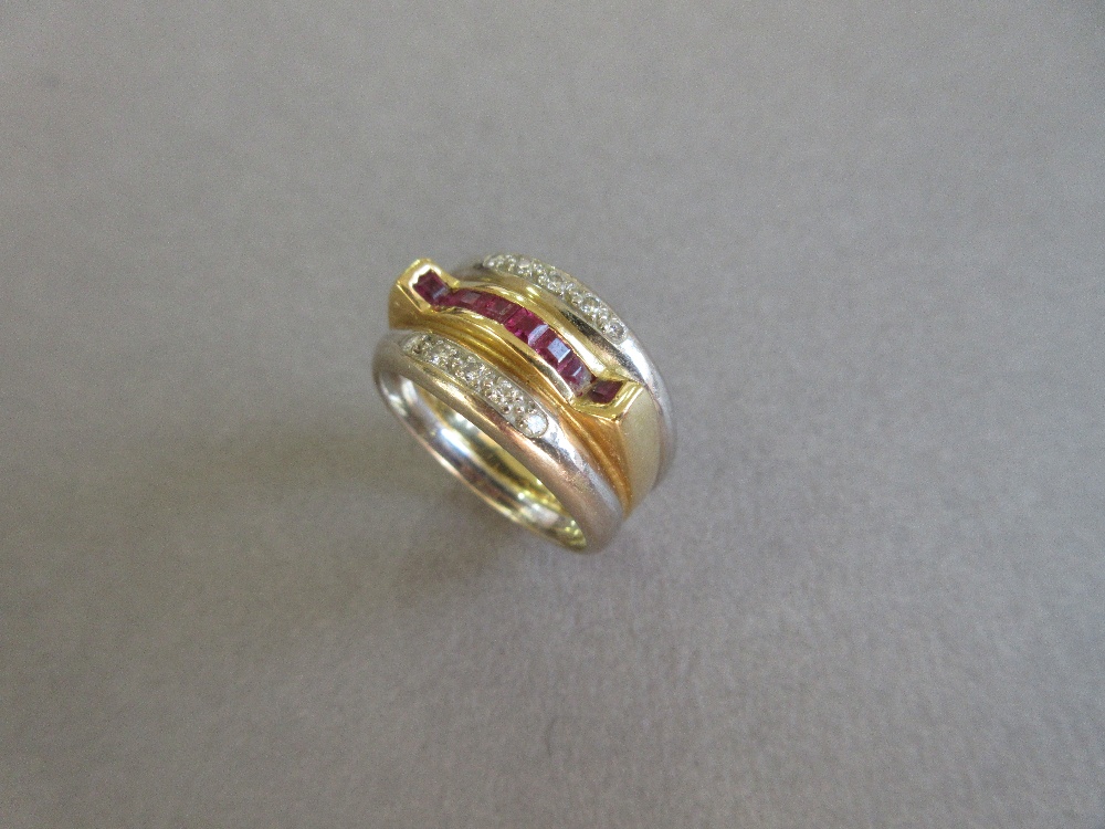 A modern ruby and diamond band ring, the central band of yellow precious metal channel set to the