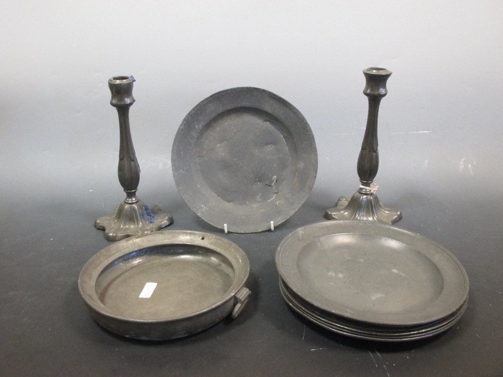 Seven 18th/19th century pewter plates, a warming dish base and a pair of candlesticks