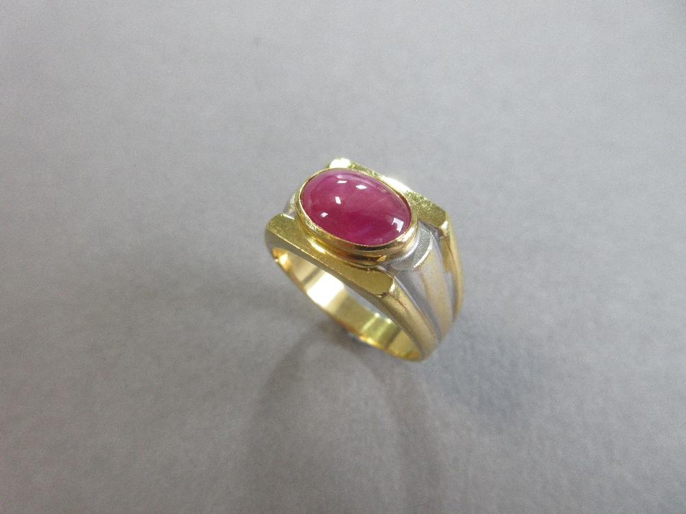 A star ruby single stone ring, the oval cabochon ruby set horizontally in a collet on a flat