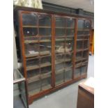 A mahogany bookcase with double cornice enclosed by three full length glazed doors with moulded