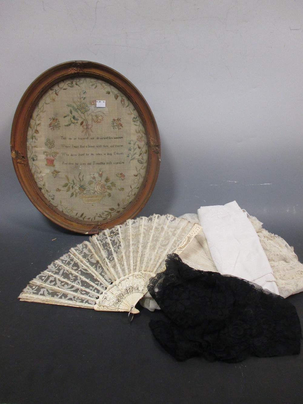 A Georgian oval needlework sampler, a quantity of linen including two unused Irish linen