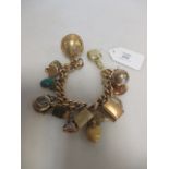 A charm bracelet stamped 18k with an assortment of mixed grade gold charms and others (gross 101g)