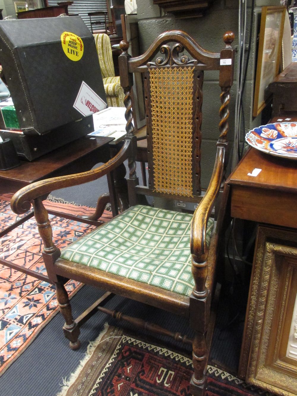 A Jacobean style open armchair with carved and caned back outswept arms, needlepoint seat and turned
