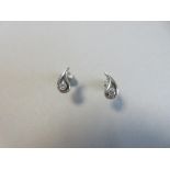 A pair of contemporary single stone diamond earstuds set in a platinum drop, each pierced comma-