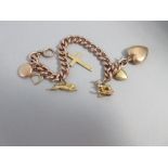An antique charm bracelet, the curb link chain of rose precious metal stamped '9ct', with seven