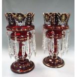 A pair of Victorian ruby glass lustres, each gilded, painted and hung with prismatic drops, under