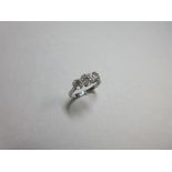 A three stone diamond and platinum ring, the graduated old round brilliant cut diamonds claw set