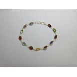 A multi gemset bracelet, designed as a line of spectacle set oval cut gems, garnets alternating with
