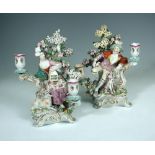 A pair of 18th century Derby porcelain figural two branch candlesticks, circa 1770, emblematic of