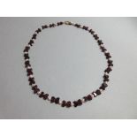 A garnet and seed pearl necklace, composed of half moon faceted garnets strung in opposing pairs