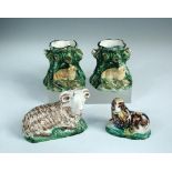 A pair of 18th century creamware spill vases, circa 1790, modelled as lambs resting against tree