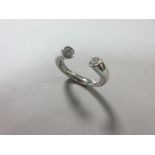 A contemporary two stone diamond ring set in platinum, designed as an incomplete hoop, the oval