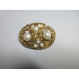 A contemporary abstract brooch set with cultured pearls, designed as two reciprocating scrolls