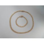 A 9ct gold necklace and bracelet suite, each with three lines of spaced brick links, to masked