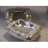 A pair of sterling silver bon bon dishes the repousse floral border with shaped dish and monogram,