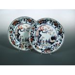 A pair of 18th century Imari plates, each with central roundel of a vase on a rock ledge outside a