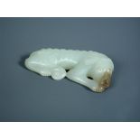 A nephrite jade sleeping dog pendant, the pale green hound with a grey muzzle, its collar tied