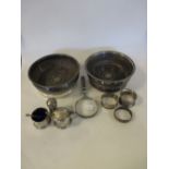 A small silver three piece silver condiment set, three silver napkin rings, a hand magnifying