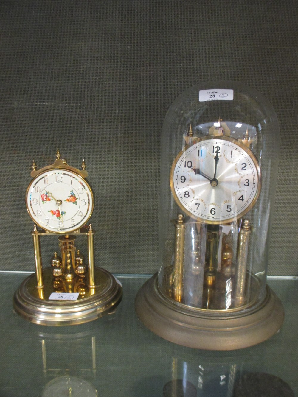 Two anniversary clocks, one under dome