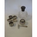 A silver mounted cut glass scent bottle, five silver napkin rings, a silver topped glass match