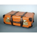 A Globe-trotter 20" pull-along suitcase, finished in orange with chestnut corners, straps and
