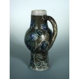 A Martin Brothers stoneware jug, the bulbous body decorated with blue flowerheads to a green ground,