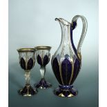 A 19th century Bohemian glass ewer and two goblets, the fluted ovoid bodies enamelled in blue with