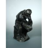 After Rodin, a bronze figure of 'The Thinker', the naked man sits with his chin in his right hand,