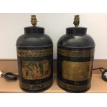 A pair of black toleware tea canisters as lamps, gilt panels central to one side of each enclosed by