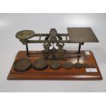 An Edwardian brass letter scale, with wooden stand and seven weights, the tray stamped 'Inland