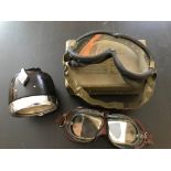 A pair of vintage leather padded frame glass goggles; a small metal cased pair of goggles; a set