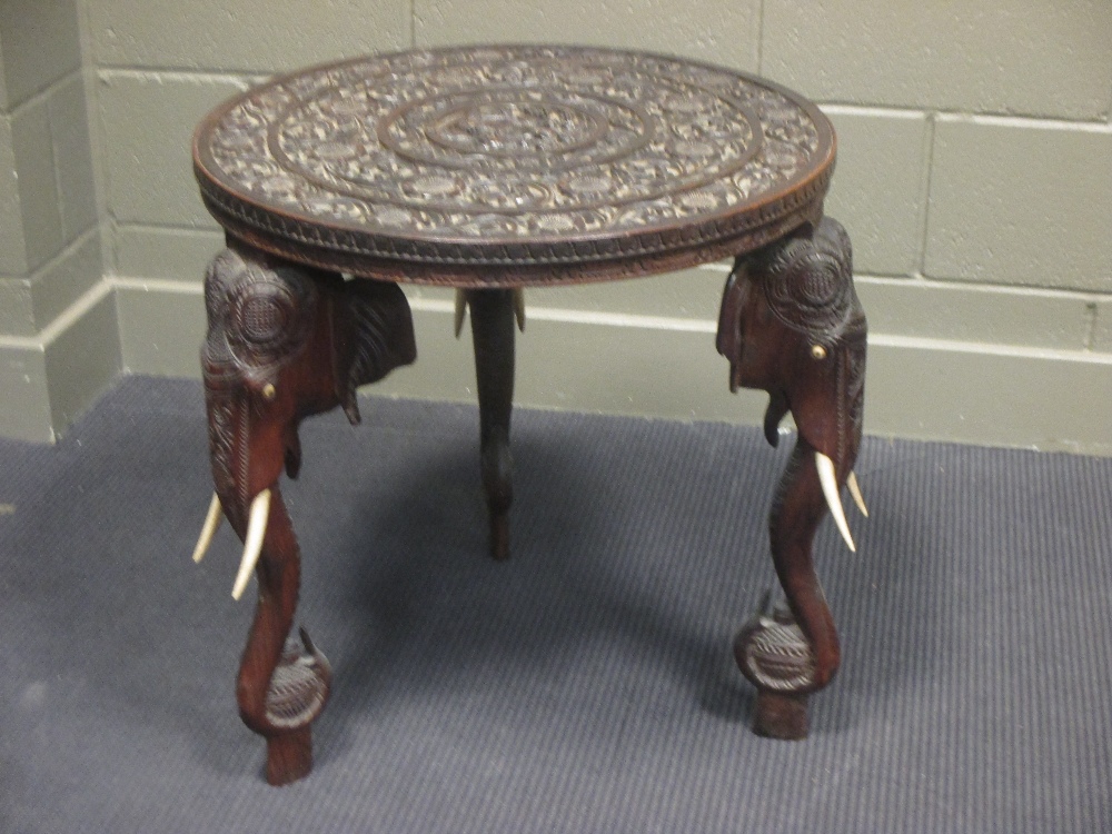 An Anglo Indian carved occasional table on elephant head supports, 62cm high