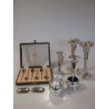 A collection of silver items including two pairs of loaded vases, two wine lables, a three piece