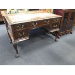 An early 20th century leather inset mahogany writing desk