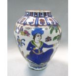 A Persian pottery ovoid vase, painted with seated figures in a landscape with a town in the