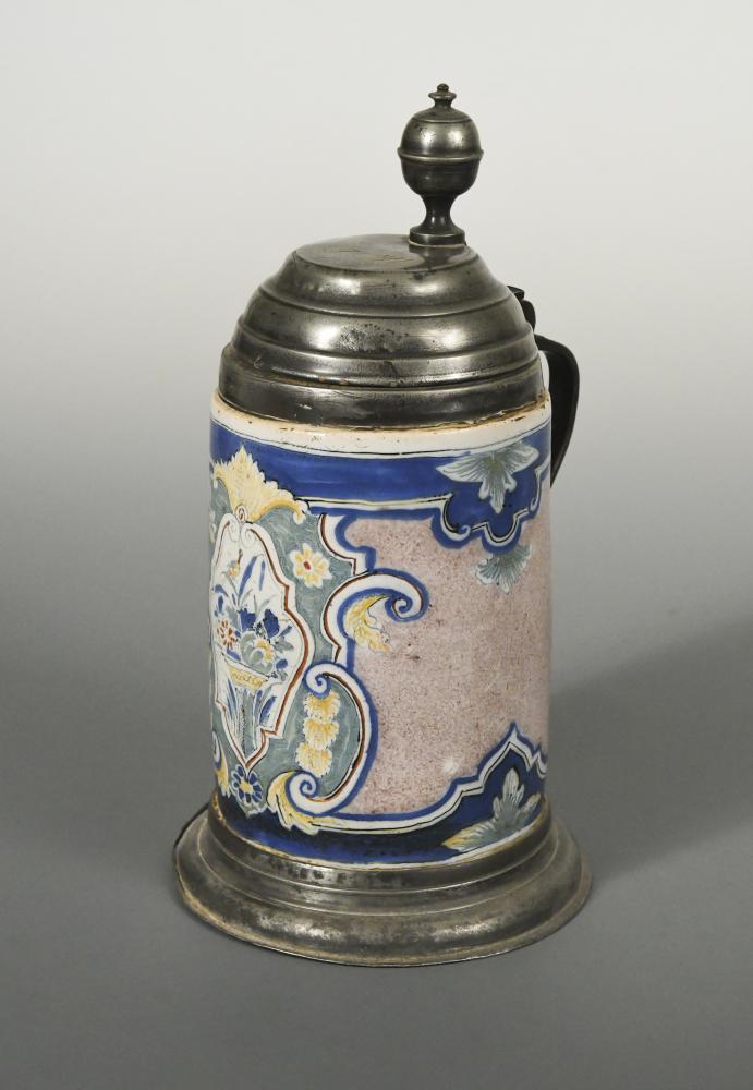 An 18th century German faience and pewter mounted tankard, the cylindrical body decorated with a
